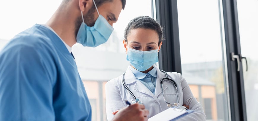 A doctor and nurse reviewing information on a clipboard