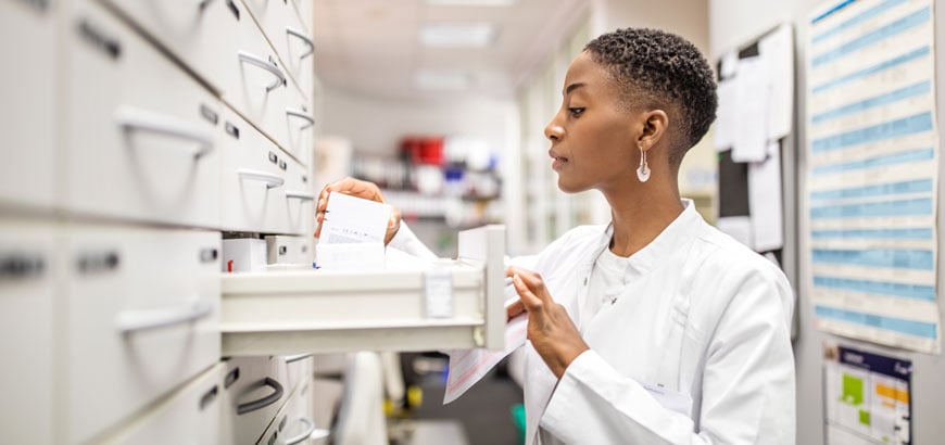 Female pharmacist looking for medicines on a shelf.