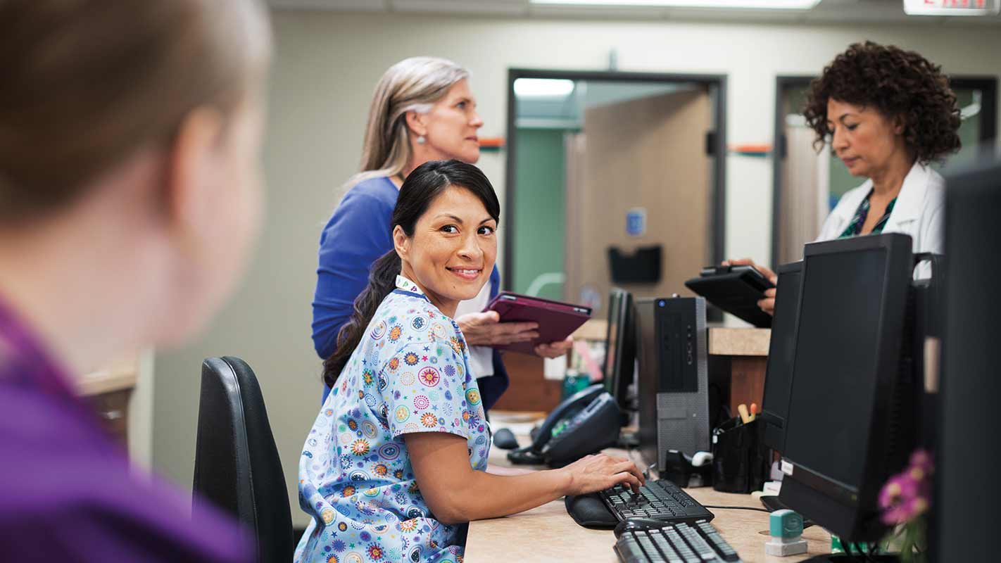 A doctor and physician office workers gathered around a desk