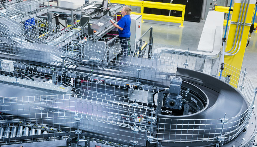 An employee works on the control panel for a large conveyor belt in a warehouse