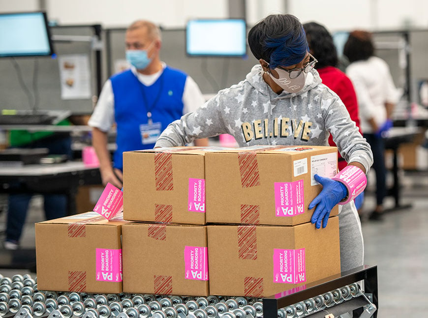 Employee moving boxes of vaccines through a warehouse