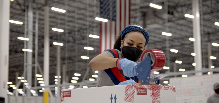 A worker sealing a box with tape in a warehouse